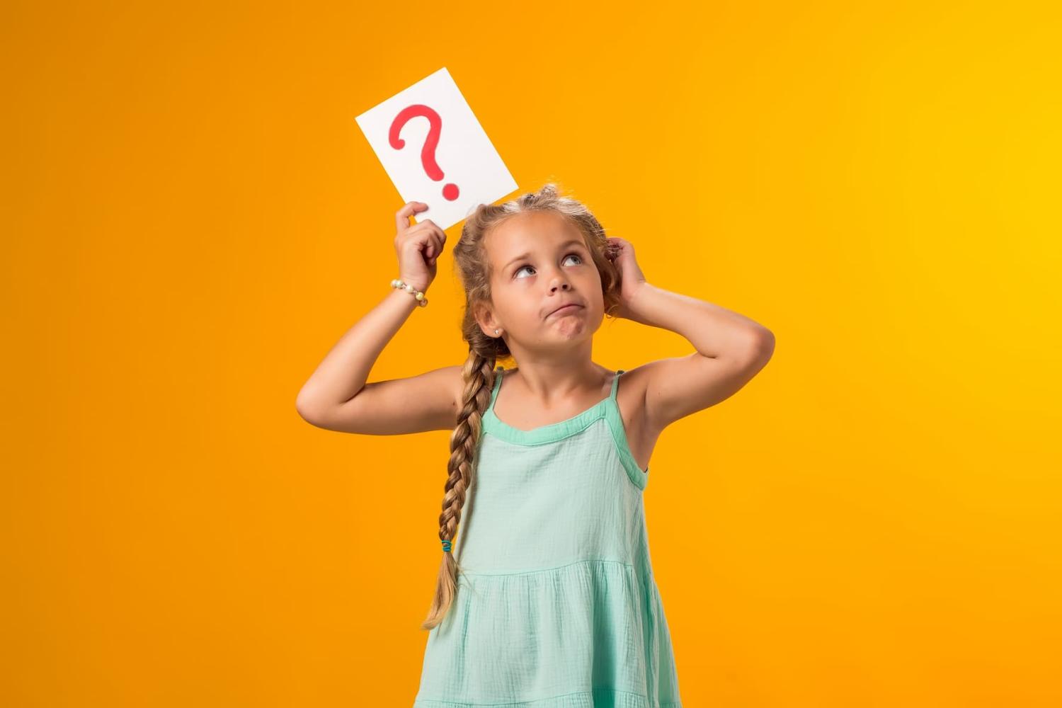 A girl is shown holding question mark card and scratching her head.