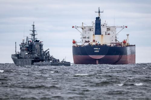 A small ship floats next to a large oil tanker on the water