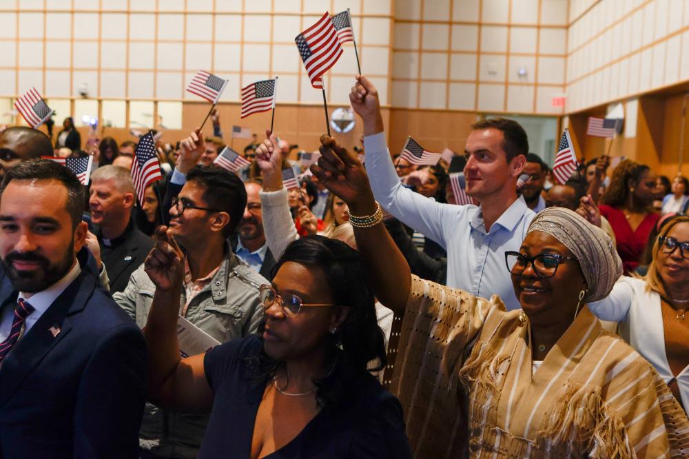 Newly sworn-in U.S. citizens wave American flags during a naturalization ceremony at the John F. Kennedy Presidential Library in Boston, Massachusetts